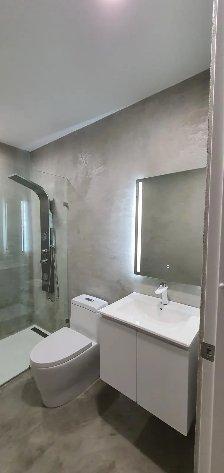 Baño con ducha moderna y acabado gris continuo