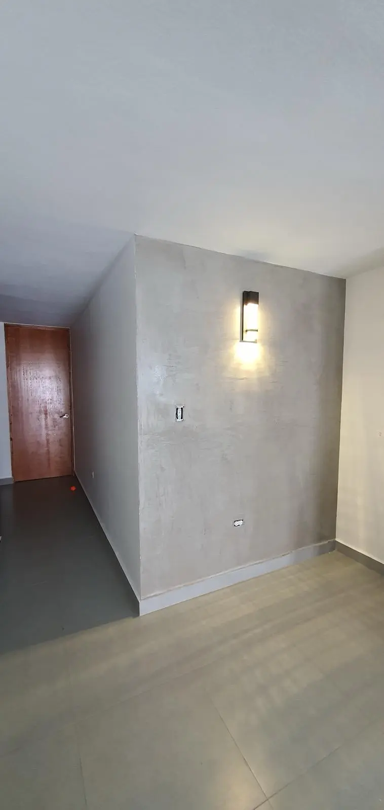 Pared focal terminada en cemento pulido con aplique de luz