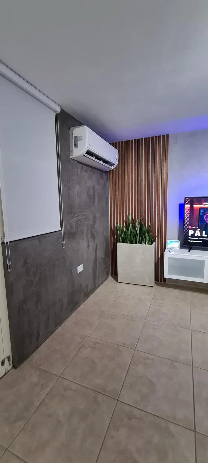 Sala moderna con cemento pulido, listones de madera e iluminación ambiental