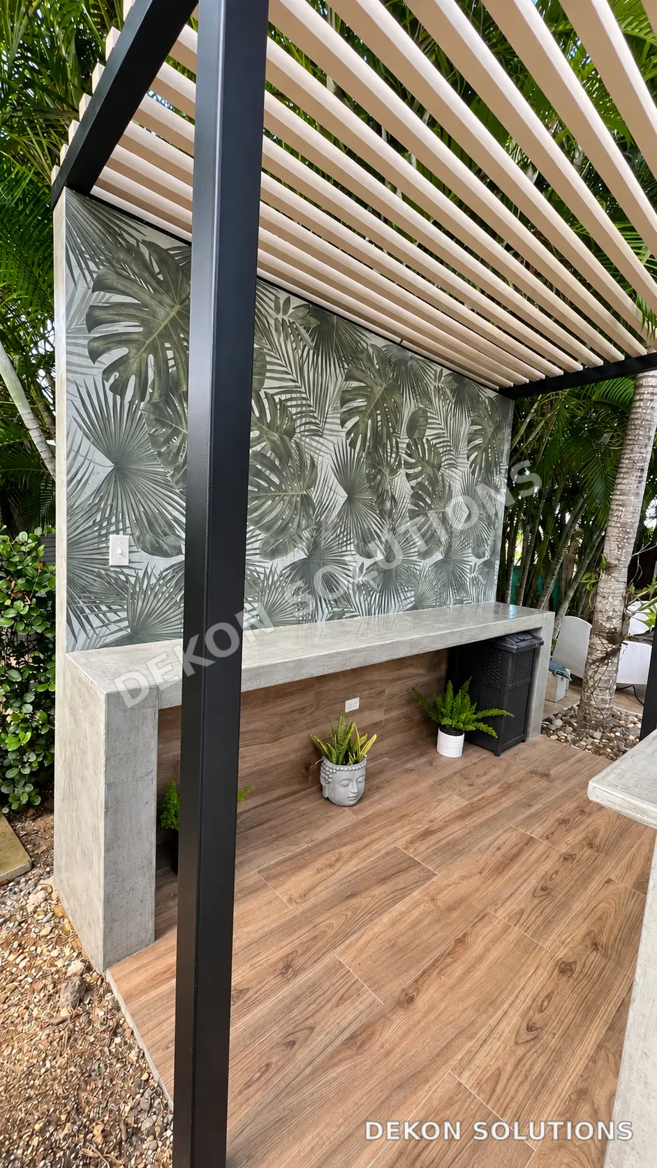 Barra exterior bajo pérgola con acabado en cemento y pared tropical
