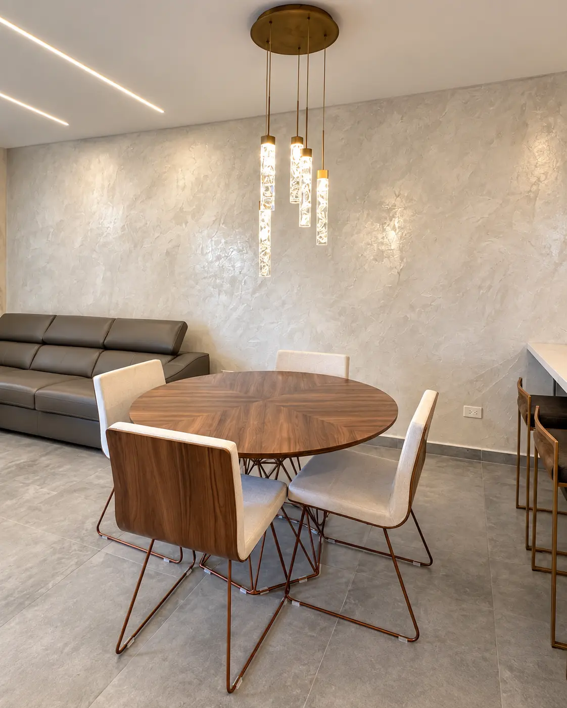 Comedor moderno con pared texturizada en tono claro e iluminación cálida