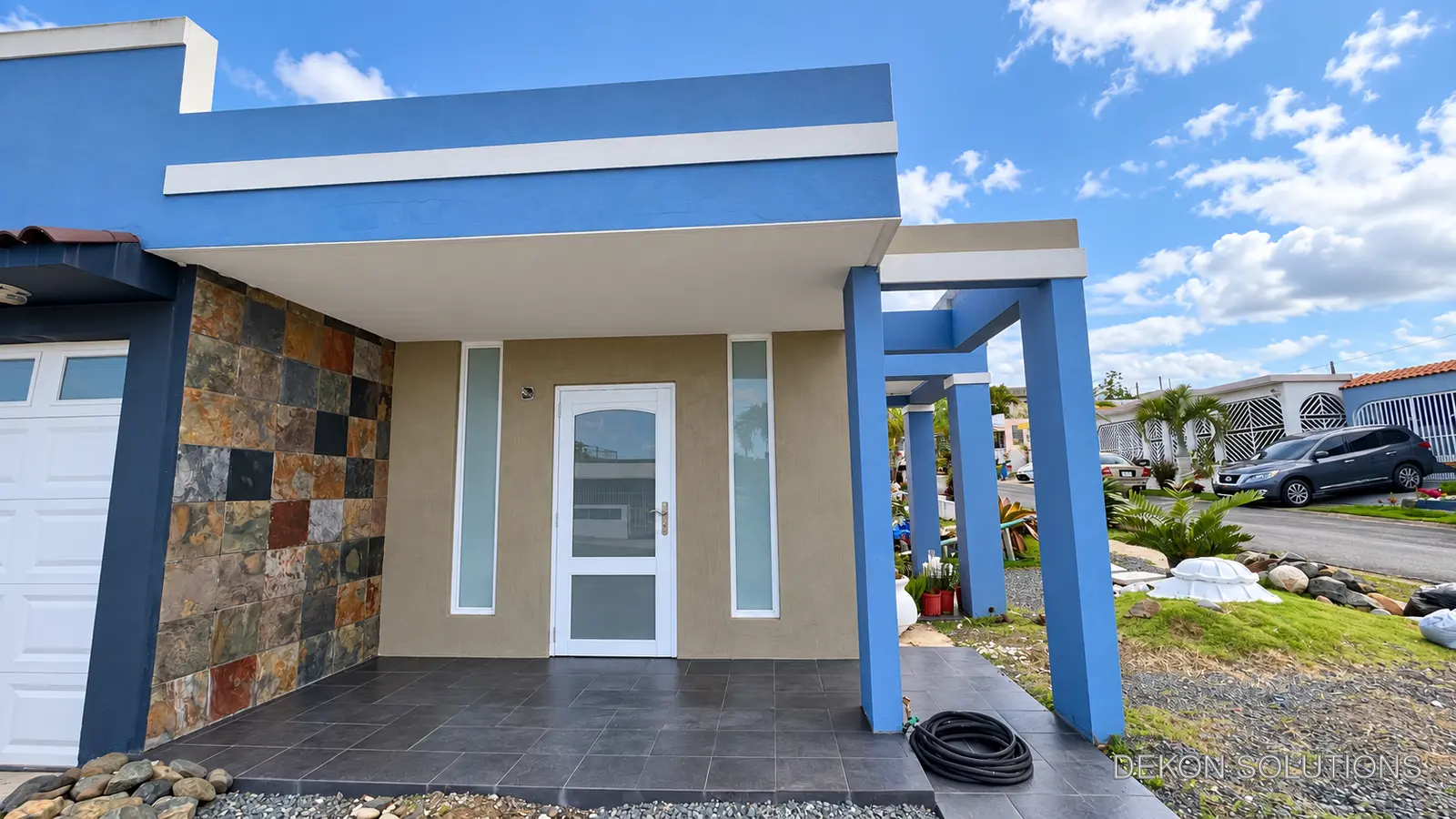 Fachada azul con acabado de cemento decorativo en la entrada
