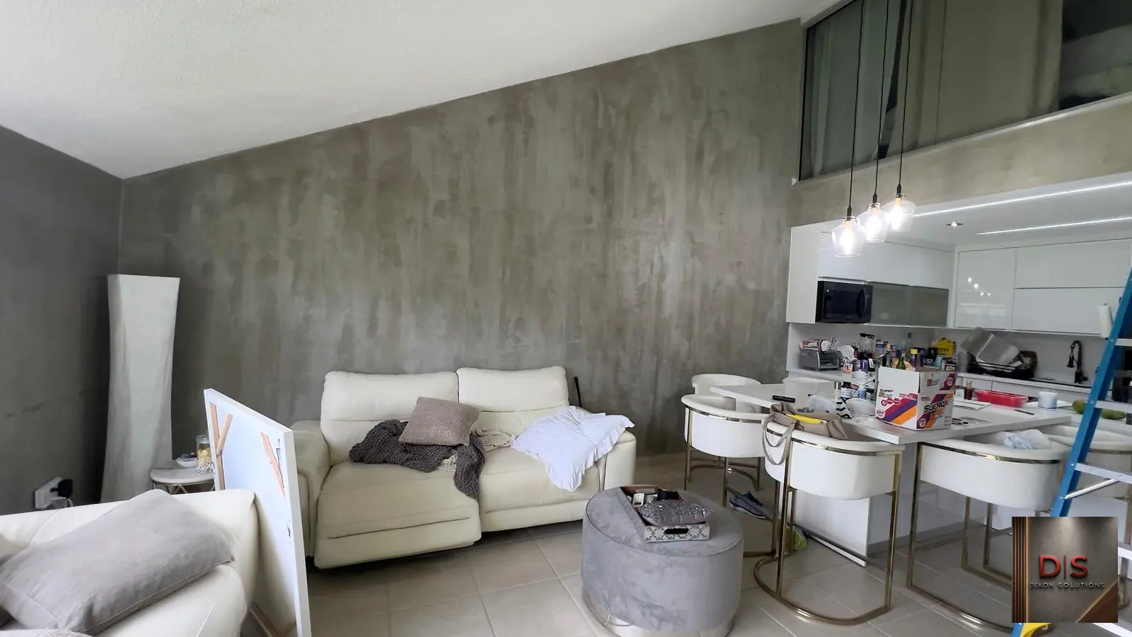 Sala y cocina integradas con pared amplia en cemento pulido