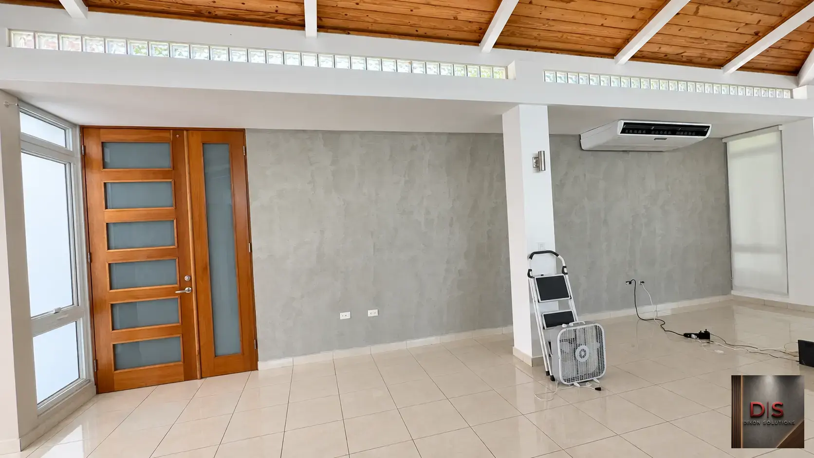 Salón amplio con paredes de cemento pulido y techo de madera